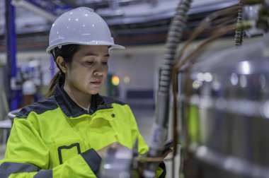 Ameliyathanede çalışan Asyalı mühendis. Taylandlılar kask takar. Adam özenle ve sabırla çalışmış, kadın hidrojen tankındaki valf düzenleyicisini kontrol etmiş..