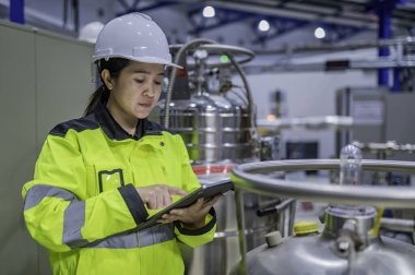 Ameliyathanede çalışan Asyalı mühendis. Taylandlılar kask takar. Adam özenle ve sabırla çalışmış, kadın hidrojen tankındaki valf düzenleyicisini kontrol etmiş..