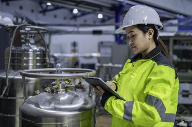 Ameliyathanede çalışan Asyalı mühendis. Taylandlılar kask takar. Adam özenle ve sabırla çalışmış, kadın hidrojen tankındaki valf düzenleyicisini kontrol etmiş..