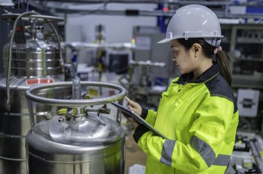 Ameliyathanede çalışan Asyalı mühendis. Taylandlılar kask takar. Adam özenle ve sabırla çalışmış, kadın hidrojen tankındaki valf düzenleyicisini kontrol etmiş..