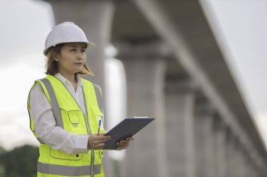 Otoyol köprüsü inşaatında çalışan Asyalı bir kadın mühendis. Sınır ötesi inşaatı denetleyen memur.