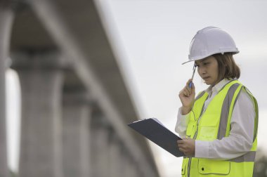 Otoyol köprüsü inşaatında çalışan Asyalı bir kadın mühendis. Sınır ötesi inşaatı denetleyen memur.