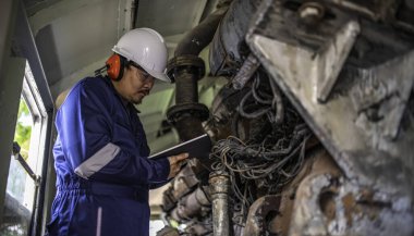 Makine mühendisi fabrikadaki büyük makineleri inceliyor. Demiryolu motor bakım teknisyeni, motor tamircisi.