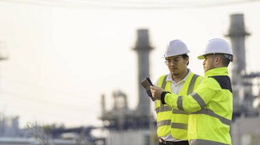 Petrol ve gaz rafinerisi fabrikasında çalışan Asyalı grup petrokimya mühendisleri. İşçi erkek mühendisler elektrik santrali enerji üretiminde kontrolde çalışıyorlar.