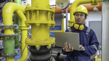 Isıtma tesisinde bakım teknisyeni. Petrokimya işçisi fabrikadaki gaz ve petrol boru hatlarının işletilmesini denetliyor. Mühendis işitme koruyucuyu birçok boruyla aynı odaya koydu.
