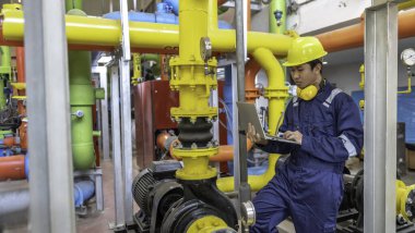 Isıtma tesisinde bakım teknisyeni. Petrokimya işçisi fabrikadaki gaz ve petrol boru hatlarının işletilmesini denetliyor. Mühendis işitme koruyucuyu birçok boruyla aynı odaya koydu.