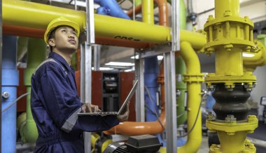 Isıtma tesisinde bakım teknisyeni. Petrokimya işçisi fabrikadaki gaz ve petrol boru hatlarının işletilmesini denetliyor. Mühendis işitme koruyucuyu birçok boruyla aynı odaya koydu.