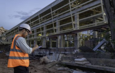 Büyük bir inşaat projesinin şantiyesinde çalışan Asyalı mühendis. Taylandlılar. İnşaat alanında fazla mesai