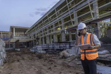 Büyük bir inşaat projesinin şantiyesinde çalışan Asyalı mühendis. Taylandlılar. İnşaat alanında fazla mesai