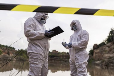Su analizi üzerinde çalışan koruyucu üniforma giyen bilim adamları ya da biyologlar. Çevre mühendisleri tehlikeli alanlarda su kalitesini kontrol ederler.