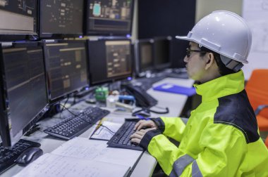 Büyük Endüstri Fabrikası Kadın Bilgisayar Mühendisi Kişisel Bilgisayar 'da çalışıyor. Kontrol makinesi için program kodluyor. Taylandlılar dört monitörle çalışıyorlar. Ciddi ile çalışan programcı