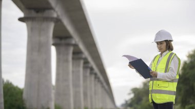 Otoyol köprüsü inşaatında çalışan Asyalı bir kadın mühendis. Sınır ötesi inşaatı denetleyen memur.