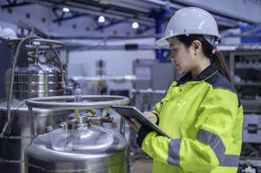 Ameliyathanede çalışan Asyalı mühendis. Taylandlılar kask takar. Adam özenle ve sabırla çalışmış, kadın hidrojen tankındaki valf düzenleyicisini kontrol etmiş..