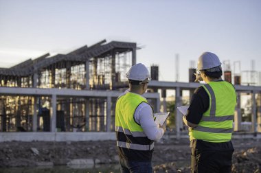 Büyük bir inşaat projesinde çalışan iki Asyalı mühendis. Taylandlılar. İnşaat alanında fazla mesai yapıyorum. Mühendislerden oluşan bir ekip olay yerinde...