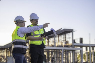 Büyük bir inşaat projesinde çalışan iki Asyalı mühendis. Taylandlılar. İnşaat alanında fazla mesai yapıyorum. Mühendislerden oluşan bir ekip olay yerinde...