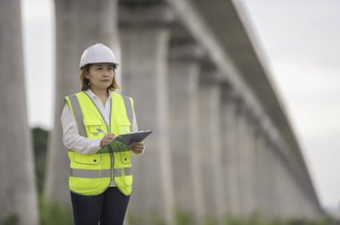 Otoyol köprüsü inşaatında çalışan Asyalı bir kadın mühendis. Sınır ötesi inşaatı denetleyen memur.