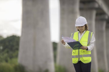 Otoyol köprüsü inşaatında çalışan Asyalı bir kadın mühendis. Sınır ötesi inşaatı denetleyen memur.