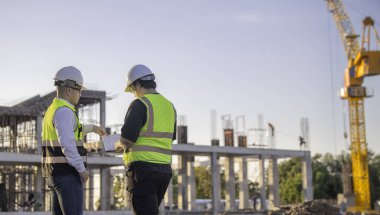 Büyük bir inşaat projesinde çalışan iki Asyalı mühendis. Taylandlılar. İnşaat alanında fazla mesai yapıyorum. Mühendislerden oluşan bir ekip olay yerinde...