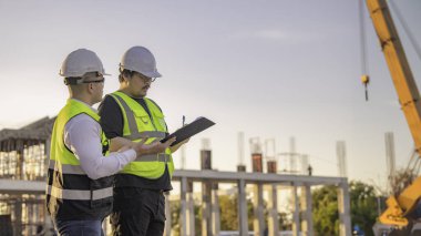Büyük bir inşaat projesinde çalışan iki Asyalı mühendis. Taylandlılar. İnşaat alanında fazla mesai yapıyorum. Mühendislerden oluşan bir ekip olay yerinde...