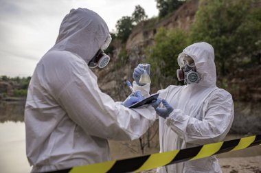 Su analizi üzerinde çalışan koruyucu üniforma giyen bilim adamları ya da biyologlar. Çevre mühendisleri tehlikeli alanlarda su kalitesini kontrol ederler.