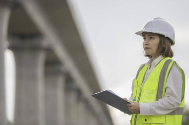Otoyol köprüsü inşaatında çalışan Asyalı bir kadın mühendis. Sınır ötesi inşaatı denetleyen memur.