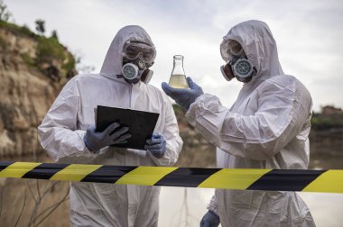 Su analizi üzerinde çalışan koruyucu üniforma giyen bilim adamları ya da biyologlar. Çevre mühendisleri tehlikeli alanlarda su kalitesini kontrol ederler.