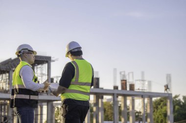 Büyük bir inşaat projesinde çalışan iki Asyalı mühendis. Taylandlılar. İnşaat alanında fazla mesai yapıyorum. Mühendislerden oluşan bir ekip olay yerinde...