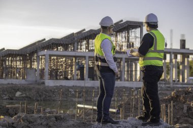 Büyük bir inşaat projesinde çalışan iki Asyalı mühendis. Taylandlılar. İnşaat alanında fazla mesai yapıyorum. Mühendislerden oluşan bir ekip olay yerinde...