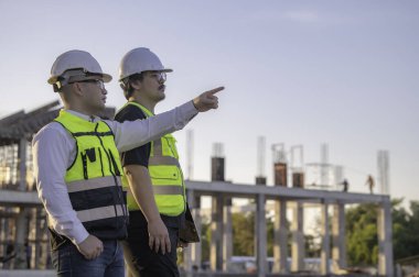 Büyük bir inşaat projesinde çalışan iki Asyalı mühendis. Taylandlılar. İnşaat alanında fazla mesai yapıyorum. Mühendislerden oluşan bir ekip olay yerinde...