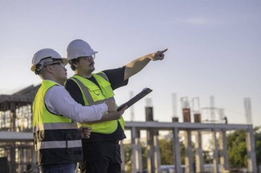 Büyük bir inşaat projesinde çalışan iki Asyalı mühendis. Taylandlılar. İnşaat alanında fazla mesai yapıyorum. Mühendislerden oluşan bir ekip olay yerinde...