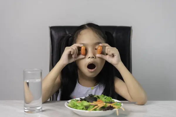 Little asian cute girl to eat healthy vegetables. Nutrition and healthy eating habits for kids concept. Child happy and like to eat vegetables.