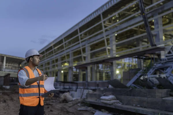 Büyük bir inşaat projesinin şantiyesinde çalışan Asyalı mühendis. Taylandlılar. İnşaat alanında fazla mesai