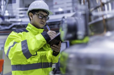 Ameliyathanede çalışan Asyalı mühendis. Taylandlılar kask takar. Çalışkanlık ve sabırla çalıştı, hidrojen tankındaki kapakçık düzenleyicisini kontrol etti..