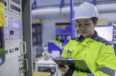 Elektrik mühendisi kadın kontrol odasındaki elektrik dağıtım kabinesindeki voltajı kontrol ediyor. Yıllık önleyici bakım. Tayland Elektrikçisi şirkette çalışıyor.
