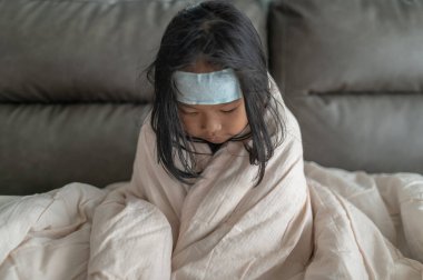 Küçük Asyalı kız evde hasta. Okuldan gelen gripten hasta.