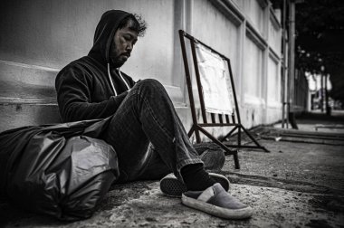 Asyalı adam yan yolda evsiz. Bir yabancı, ailesi olmadığı için yolda tek başına yaşamak zorundadır..