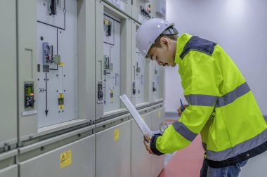Elektrik mühendisi kontrol odasındaki elektrik dağıtım kabinesindeki voltajı kontrol ediyor. Yıllık önleyici bakım. Tayland Elektrikçisi şirkette çalışıyor.