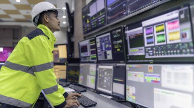 Kontrol odasında çalışan bir mühendis. Yönetici kontrol sistemi. Birçok monitörden teknisyen izleme programı