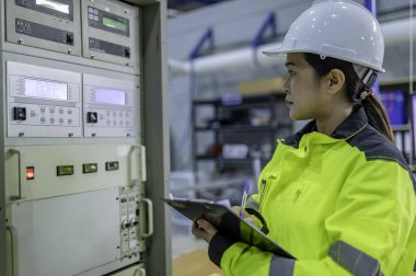 Elektrik mühendisi kadın kontrol odasındaki elektrik dağıtım kabinesindeki voltajı kontrol ediyor. Yıllık önleyici bakım. Tayland Elektrikçisi şirkette çalışıyor.