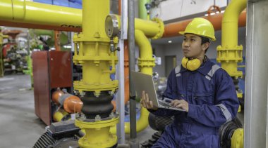 Isıtma tesisinde bakım teknisyeni. Petrokimya işçisi fabrikadaki gaz ve petrol boru hatlarının işletilmesini denetliyor. Mühendis işitme koruyucuyu birçok boruyla aynı odaya koydu.