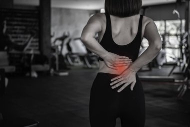 Asyalı zayıf kadın spor salonunda fitness oynuyor. Egzersiz yüzünden acı çekiyor.