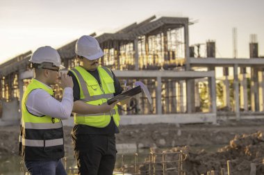 Büyük bir inşaat projesinde çalışan iki Asyalı mühendis. Taylandlılar. İnşaat alanında fazla mesai yapıyorum. Mühendislerden oluşan bir ekip olay yerinde...
