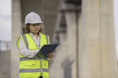 Otoyol köprüsü inşaatında çalışan Asyalı bir kadın mühendis. Sınır ötesi inşaatı denetleyen memur.