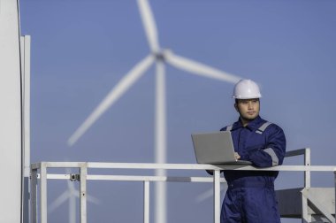 Rüzgar türbini çiftliği güç jeneratörü istasyonunda çalışan ve raporu tutan bir mühendis. Taylandlılar.