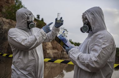 Su analizi üzerinde çalışan koruyucu üniforma giyen bilim adamları ya da biyologlar. Çevre mühendisleri tehlikeli alanlarda su kalitesini kontrol ederler.