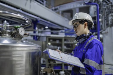 Ameliyathanede çalışan Asyalı mühendis. Taylandlılar kask takar. Çalışkanlık ve sabırla çalıştı, hidrojen tankındaki kapakçık düzenleyicisini kontrol etti..