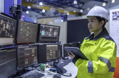 Büyük Endüstri Fabrikası Kadın Bilgisayar Mühendisi Kişisel Bilgisayar 'da çalışıyor. Kontrol makinesi için program kodluyor. Taylandlılar dört monitörle çalışıyorlar. Ciddi ile çalışan programcı