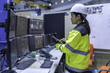 Büyük Endüstri Fabrikası Kadın Bilgisayar Mühendisi Kişisel Bilgisayar 'da çalışıyor. Kontrol makinesi için program kodluyor. Taylandlılar dört monitörle çalışıyorlar. Ciddi ile çalışan programcı