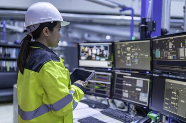 Büyük Endüstri Fabrikası Kadın Bilgisayar Mühendisi Kişisel Bilgisayar 'da çalışıyor. Kontrol makinesi için program kodluyor. Taylandlılar dört monitörle çalışıyorlar. Ciddi ile çalışan programcı