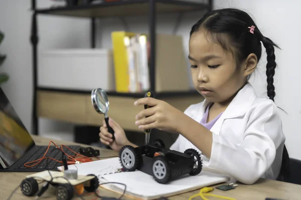 Asian littlle girl constructing and coding robot at STEM class. Fixing and repair mechanic toy car